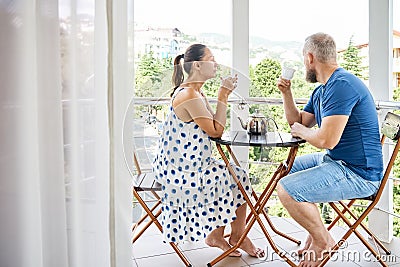 Wife and husband drinking beverage sit on hotel balcony Stock Photo