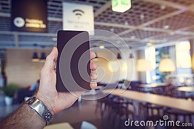 Wifi free zone. Black modern smartphone in mans hand against cafe background. Wi-fi zone in cafe. Wi fi free in restaurant Stock Photo