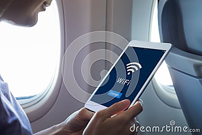 Wifi internet access in airplane during flight, passenger using tablet computer to connect to wireless network technology onboard Stock Photo