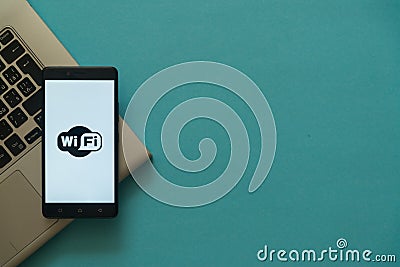 Wifi logo on smartphone placed on laptop keyboard. Editorial Stock Photo