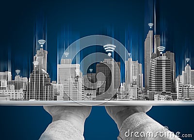 Wifi network connection and smart city concept. Hand holding digital tablet and building hologram with wifi signal sign Stock Photo