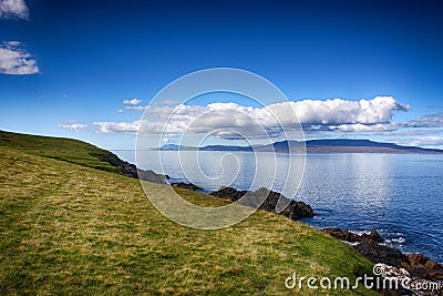 Green grass blue water and cloudy blue sky Stock Photo