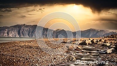 Wild beach over mountains and dramatic sky. Stock Photo