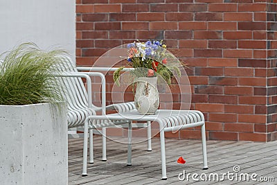 Wild flower bouquet (Cornflowers, chamomiles wheat and poppies) in terracotta vase on summer terrace. Stock Photo