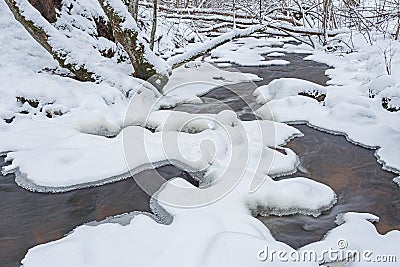 The wild frozen river in the winter wood atfter snow storm, the wild nature, ice, snow-covered stones, peace and quiet Stock Photo