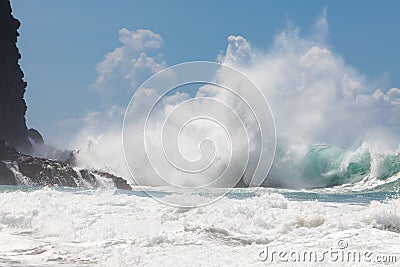 Wild, powerful wave splashing, crashing on rocky shore, under bl Stock Photo