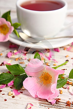 Wild rose flower and cup of tea on old rustic wooden background Stock Photo