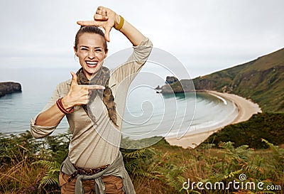 Woman hiker framing with hands in front of ocean view landscape Stock Photo