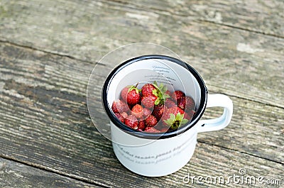 Wild strawberry in metal cup on wooden background Stock Photo