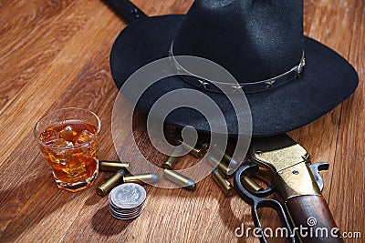 Wild west rifle and ammunitions with glass of whisky and ice with old silver dollar on wooden table Stock Photo
