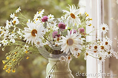 Wildflowers along with daisies in ceramic vase in vintage styl. Stock Photo
