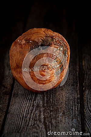 Wilted rotten apple with fungus on a wooden brown surface background Stock Photo