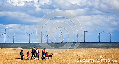 Wind farm off the coast of Yarmouth with family walking dogs on beach in Great Yarmouth, Norfolk, UK Editorial Stock Photo