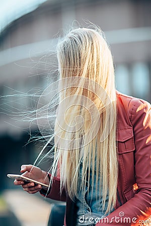 Wind in hair close face of blonde woman using her mobile phone Stock Photo
