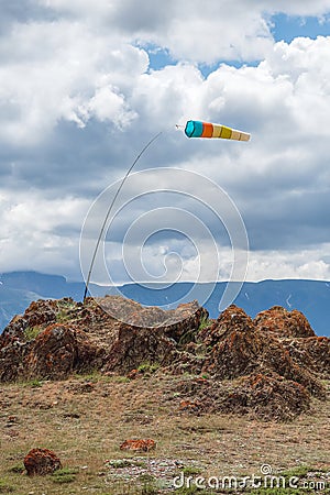 Wind sock in the mountains. Wind designator against the blue mountains. Wind sleeve flying on a blue cloudy sky Stock Photo