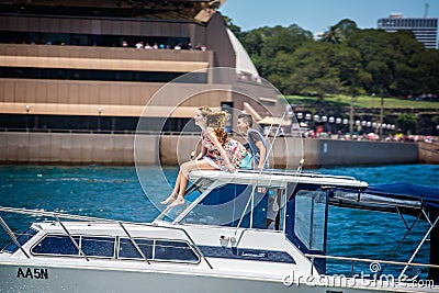 Wind swept pretty girl and young man sat on roof of speeding speed boat in front of Sydney Opera House in Sydney, Australia Editorial Stock Photo