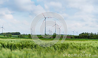 Wind turbine on green fields in summertime. Natural wind power plants and sustainable eco-friendly energy resource Stock Photo