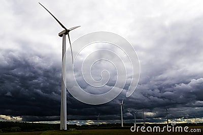 Wind turbines against dark clouds in the upcoming storm, concept Stock Photo