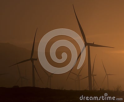 Wind turbines in blowing dust at sunset near Palm Springs CA Stock Photo