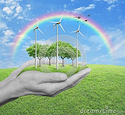 Wind turbines, grass and trees in human hands over green grass w Stock Photo