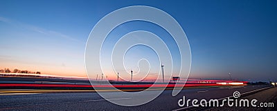 Wind turbines at sunset along highway morning commute Stock Photo