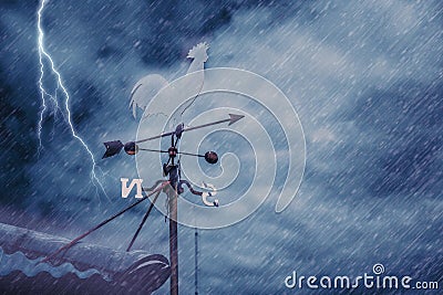 Wind vane on house roof with background of storm raining Stock Photo