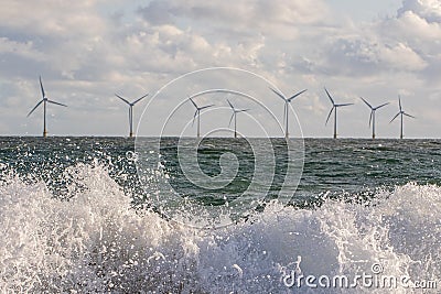 Wind and wave energy. Breaking waves with offshore windfarm turbines background Stock Photo