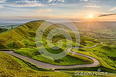 Long winding country road leading through rural countryside in the English Peak District with beautiful evening sunlight. Stock Photo
