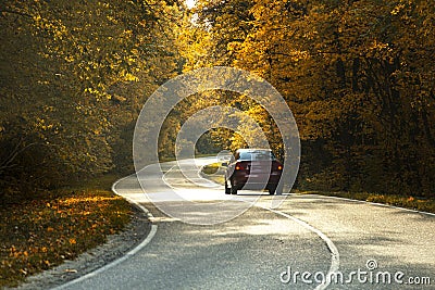 winding rual road with car inside colorful autumn forest Stock Photo