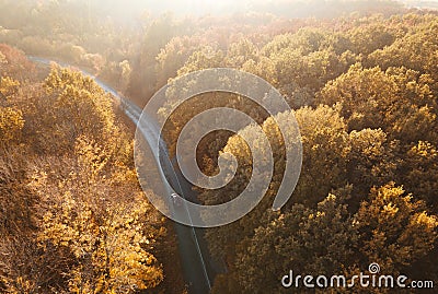 Winding rual road inside autumn forest with black car Stock Photo