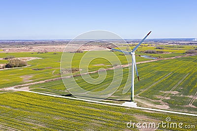 Windmill on a background of green field. Green electricity production. Alternative energy. Stock Photo