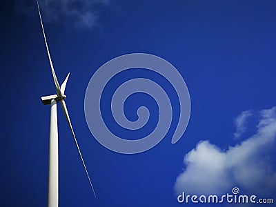 Windmill close up on blue sky and white cloud background. Wind-turbine on wind farm in rotation to generate electricity energy on Stock Photo