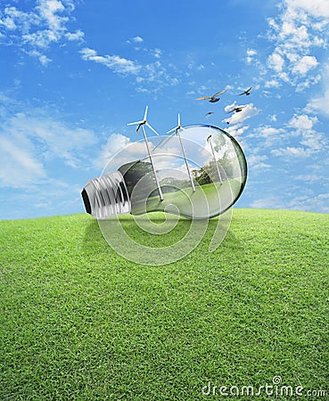 Windmill and forest inside light bulb with birds over green grass field and blue sky , Ecological concept Stock Photo