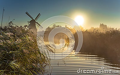 Windmill in misty marshland Stock Photo