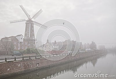 Windmill beside a misty river. Stock Photo