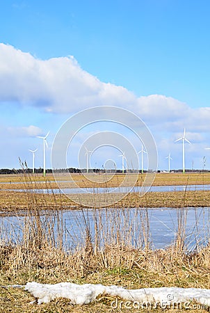 Windmill park in Latvia - view from ploughland with frozen waters. Stock Photo