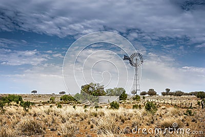 Windmill and watering point on red earth on a remote outback sheep station in far western New South Wales, Australia Stock Photo