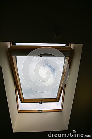 Window in the ceiling. Blue sky with clouds. Attic interior Stock Photo