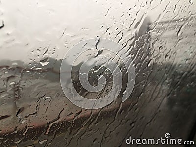 Window covered in water drops of a train moving through a landscape in rainfall Stock Photo