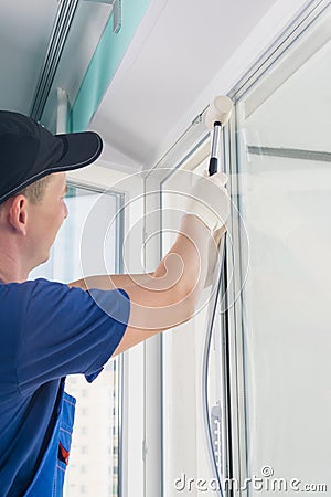 Window installation worker inserts glass into the frame and fastens the window with a rubber mallet, side view Stock Photo