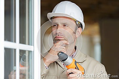 window installer in contemplation holding drill Stock Photo
