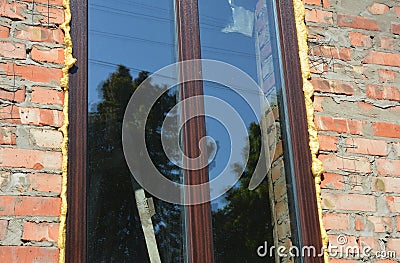 Window insulation with foam on brick wall construction. Insulate around the opening with spray foam insulation. Stock Photo