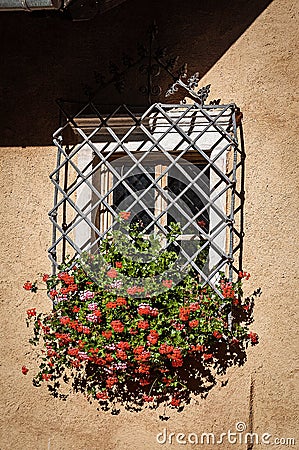 Window with red geraniums and wrought iron security bars - Trentino Italy Stock Photo