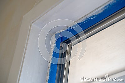 Window trim covered with blue painters tape during home renovation improvements during painting Stock Photo