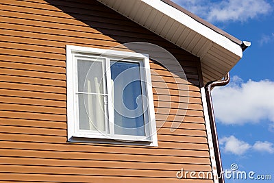 Window in wall of brown vinyl siding Stock Photo