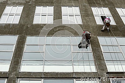 Window washers on top. Two workers hung ropes wash windows on high-rise Editorial Stock Photo