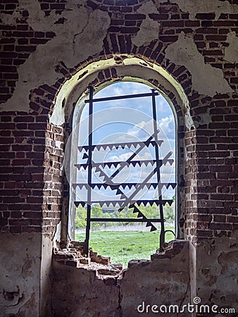 Windows of an ancient temple, in the wall of red brick, in the form of an arch. The hole in the wall is sealed with metal bars Stock Photo