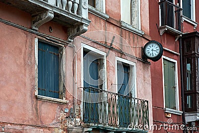 View of windows, balcony, clock and details of old cracked walls of buildings on the street in Venice, Italy Stock Photo