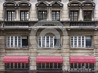 Windows in old concrete building in the center of the city with red awning Stock Photo