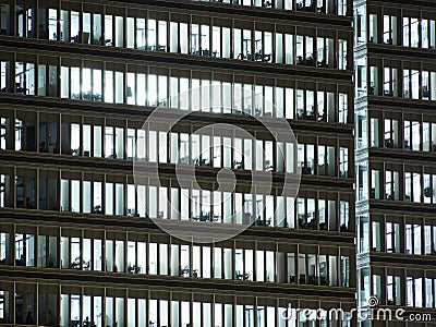 Windows of white lit offices in tall Office building viewed from outside Stock Photo